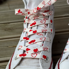 Cupid batų raištelių rašto detalė su raudonomis širdelėmis ant balto sportbačio